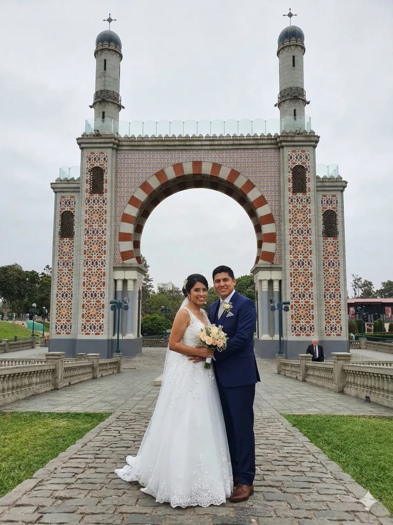 Pareja recién casada posando frente al arco morisco en el Parque de la Amistad de Surco