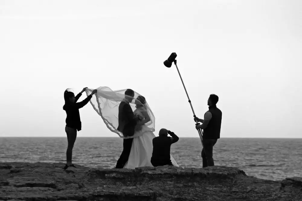Fotógrafo profesional en blanco y negro capturando a unos novios frente al mar